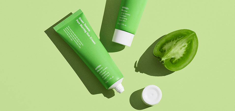 Green skincare tubes and halved tomato representing The Artistry of Skincare: Introducing SUNGBOON EDITOR, Your Korean Beauty Maestro