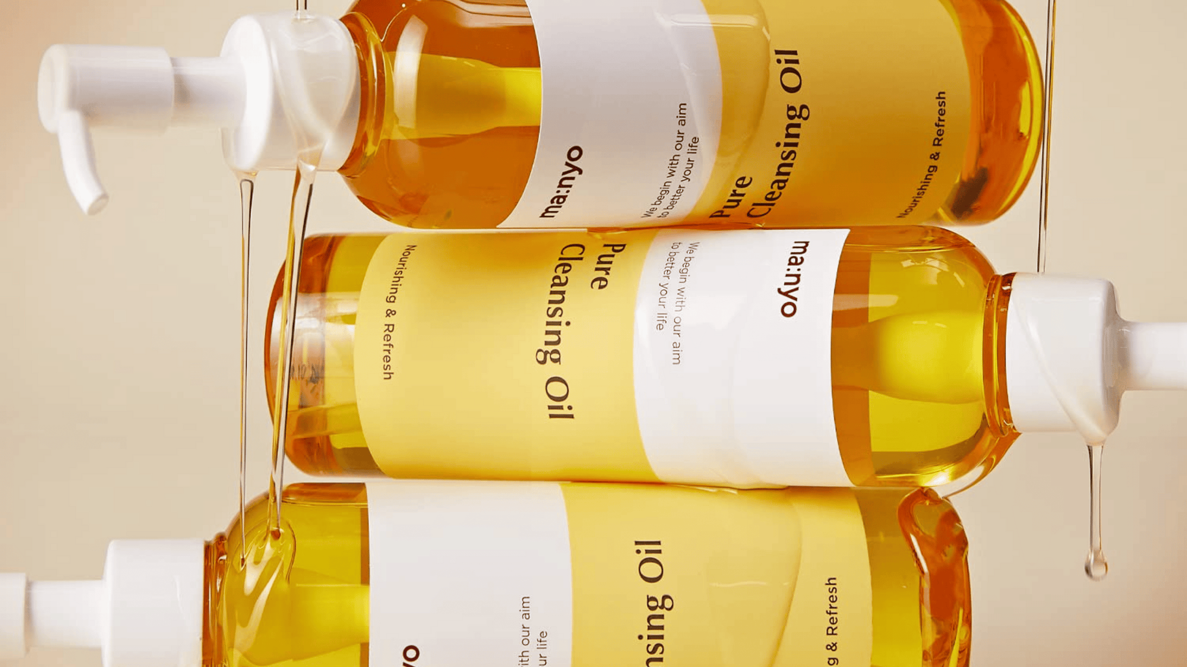 Unlocking the Secrets of MANYO: Natural and Effective Skincare with MANYO Pure Cleansing Oil bottles dripping on beige background