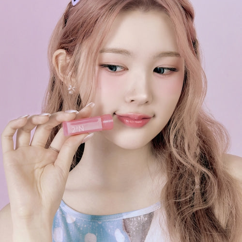 Person holding 2an Mini Glaze Bouncing Tint against a pink background.