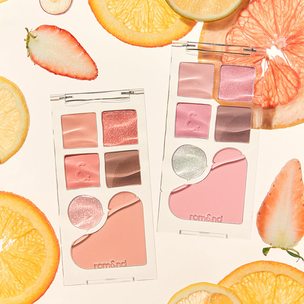 ROMAND Bare layer palette surrounded by fresh fruit slices, showcasing vibrant makeup shades and elegant packaging.