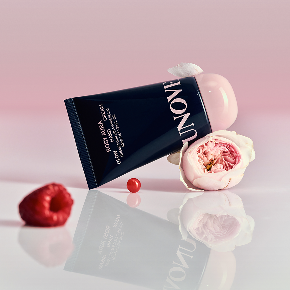 UNOVE Glow Hand Cream 40ml in pink packaging with rose and raspberry accents on a reflective surface.
