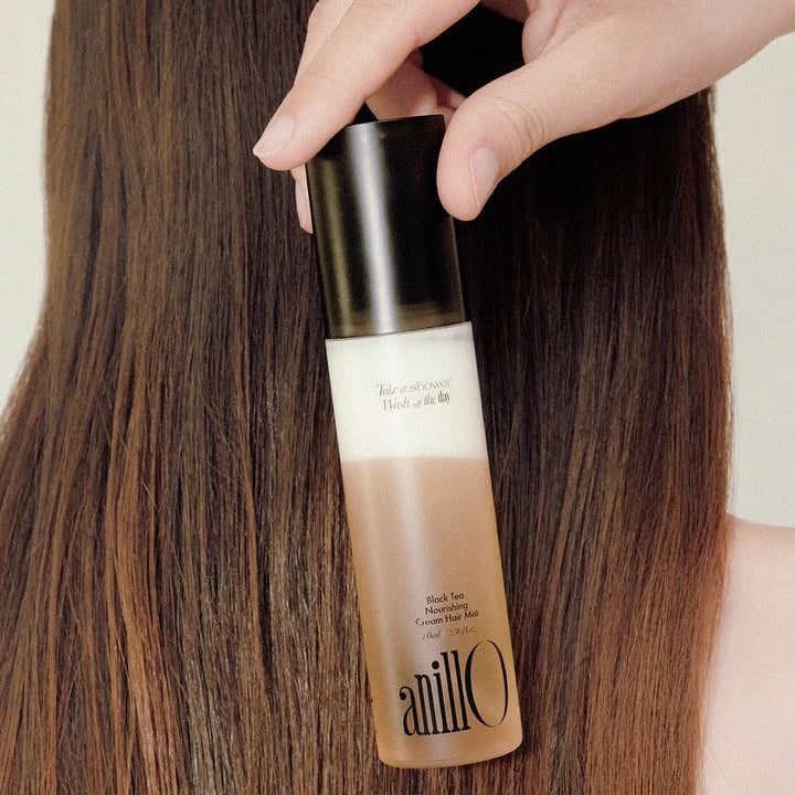 ANILLO Black Tea Nourishing Cream Hair Mist 70ml bottle shown against smooth, straight hair, emphasizing product's nourishing qualities.
