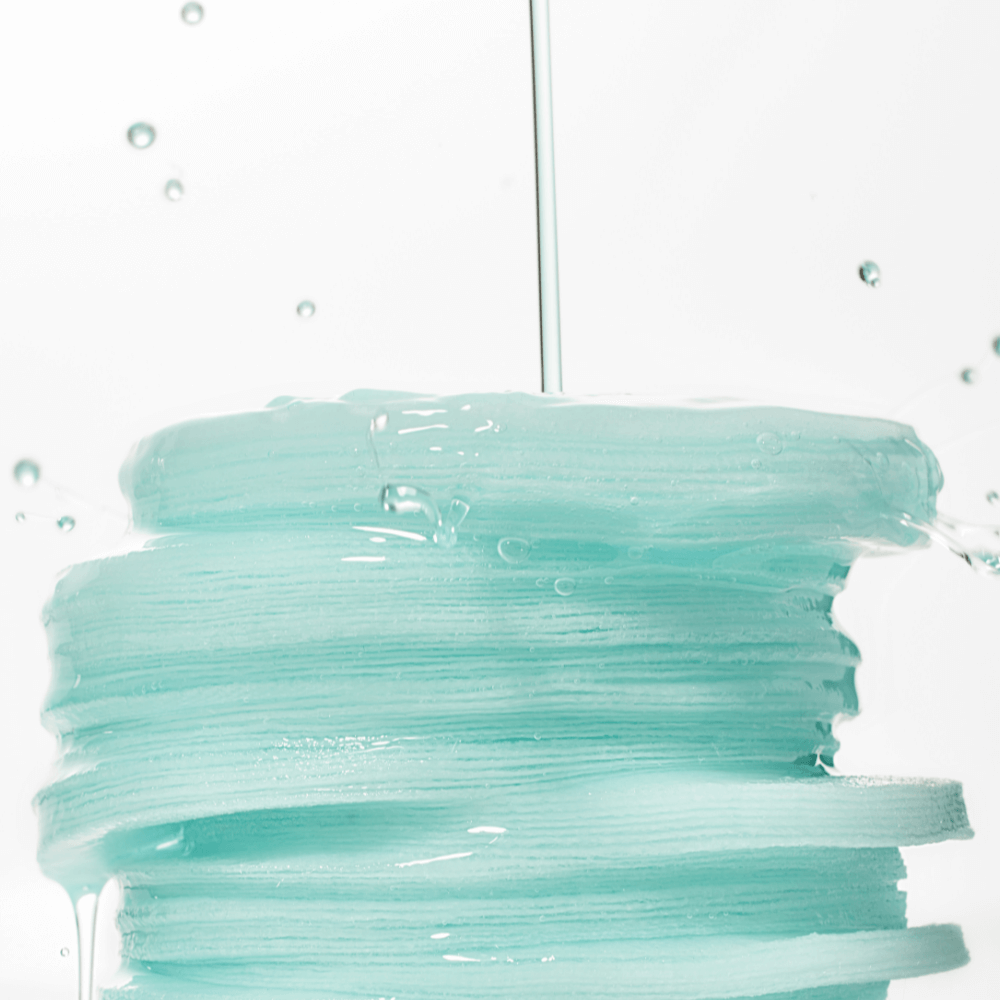 Stack of wet ANUA PDRN 100 Hyaluronic Acid Glow Pad with liquid dripping