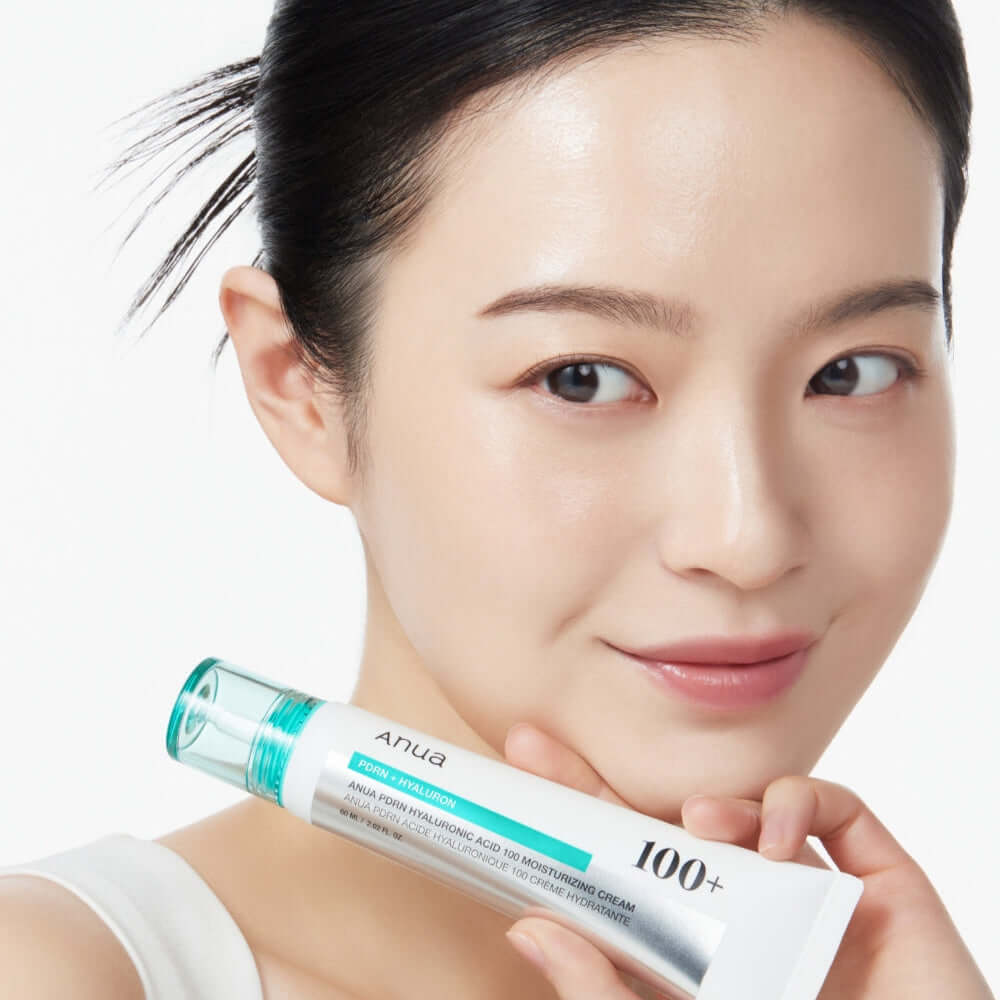 Person holding ANUA PDRN Hyaluronic Acid 100 Moisture Cream tube showcasing skincare product.