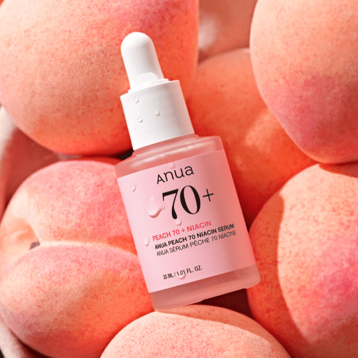 ANUA Peach 70 + Niacin Serum 30ml bottle surrounded by fresh peaches