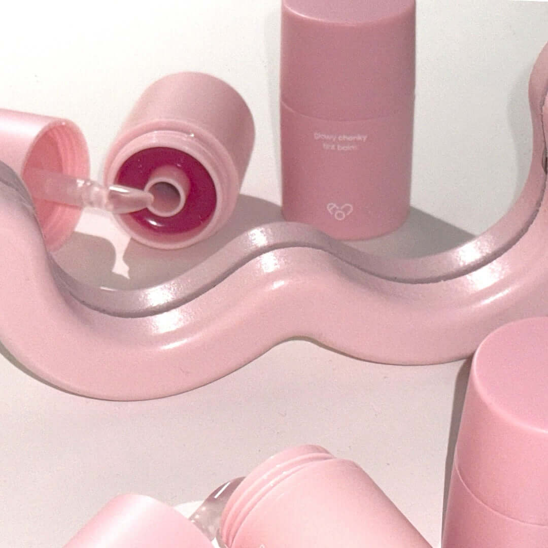 Pink AOU Glowy Chonky Tint Balm tubes with swirled design, showcasing the product's sleek and trendy packaging.