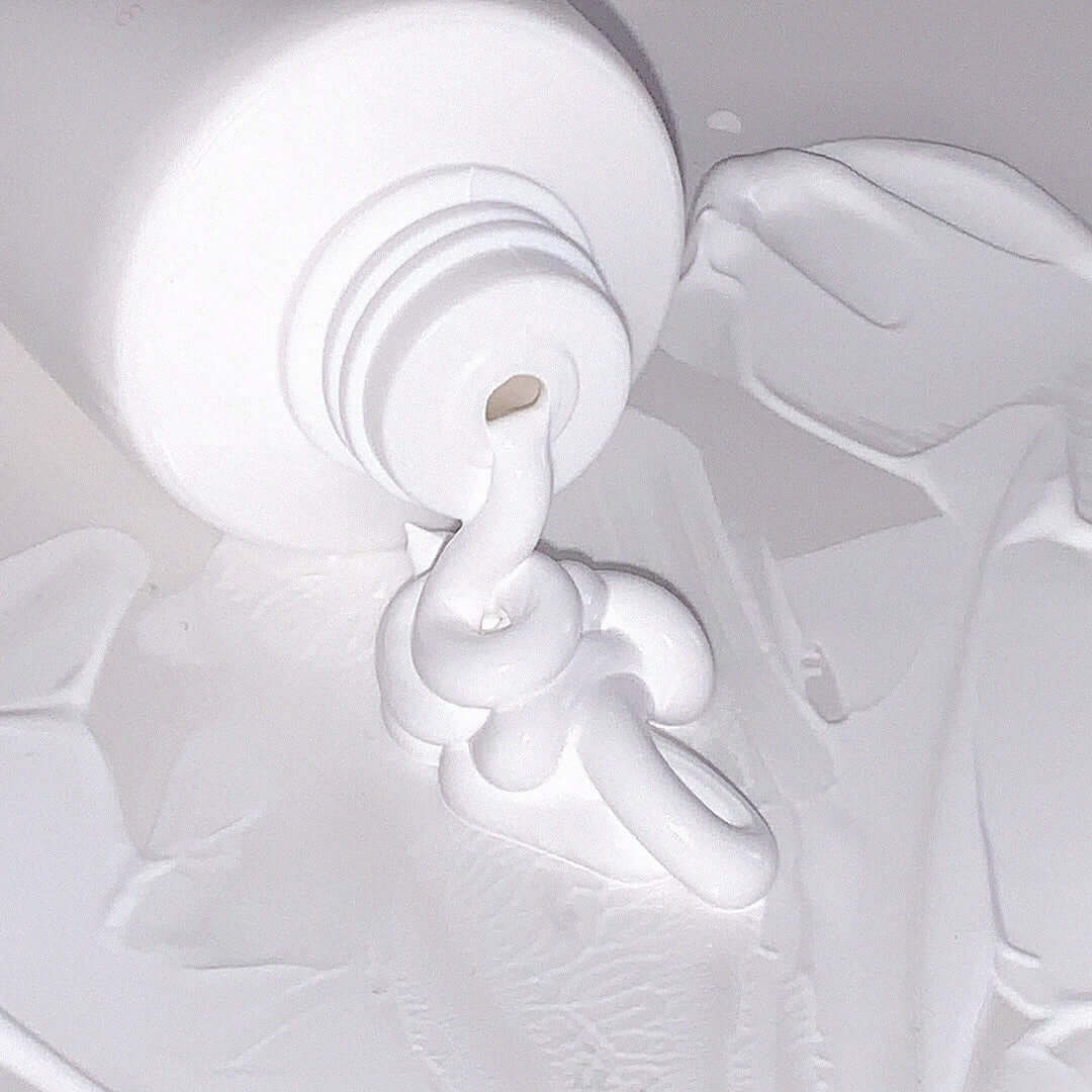 AOU Tone-Up Dazzling Cream spread out from an open tube, showcasing its texture and smoothing properties.