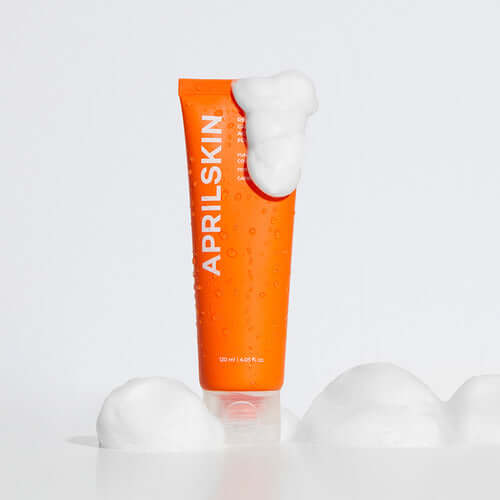 APRILSKIN Carotene Acne Foam Cleanser, orange tube with foam, skincare product for acne.