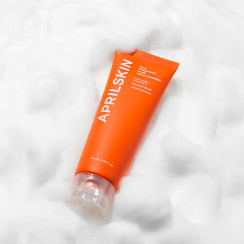 APRILSKIN Carotene Acne Foam Cleanser tube on a foamy background