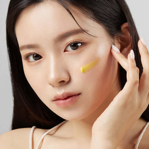 Woman applying APRILSKIN Carrotene IPMP Clearing Solution to her cheek for skincare routine.