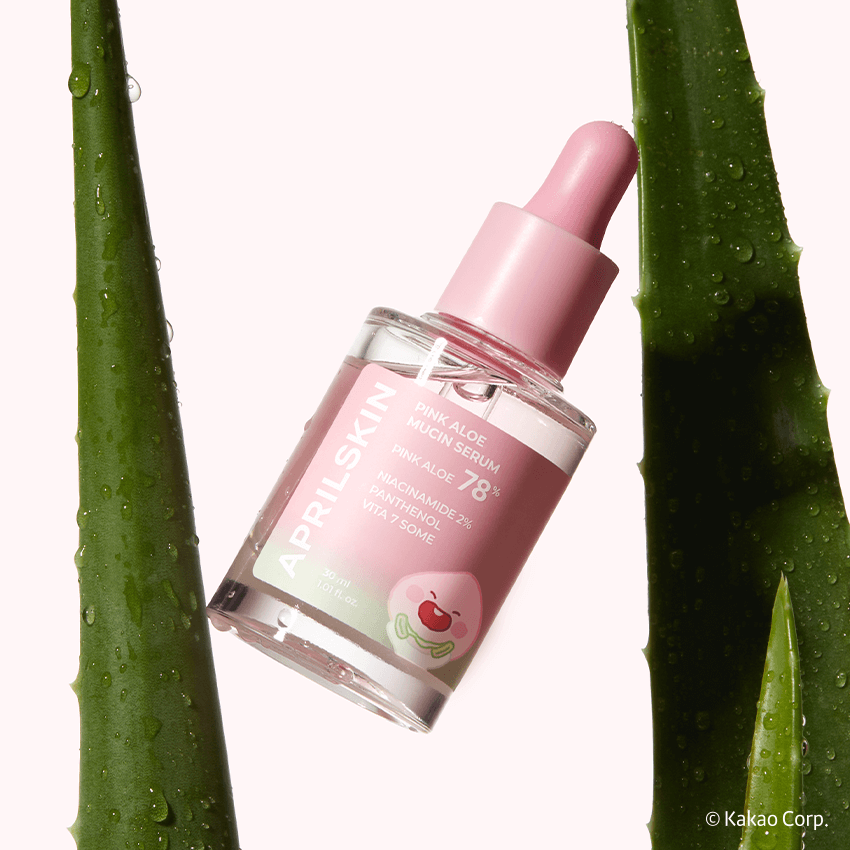 APRILSKIN Pink Aloe Mucin Serum bottle with pink dropper surrounded by green aloe leaves. Skincare and beauty product.