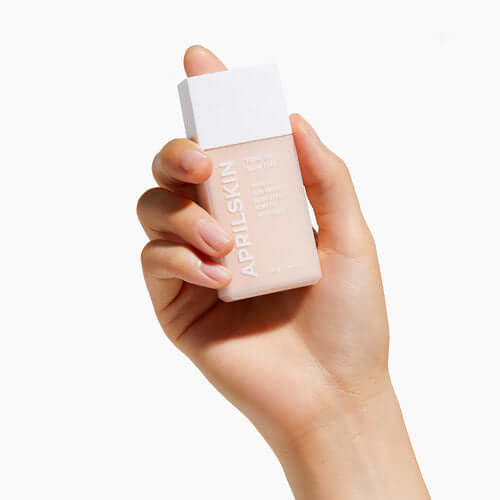 Person holding APRILSKIN Tone-Up Skin Tint bottle with white cap.