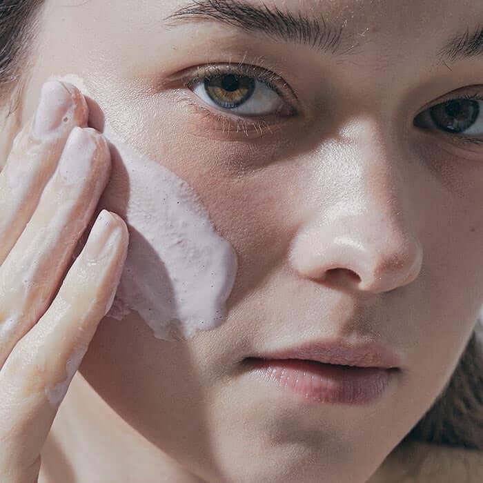 Woman applying ARENCIA Green Artisan Cleanser Rice Soap 120g to her face, highlighting skincare routine.