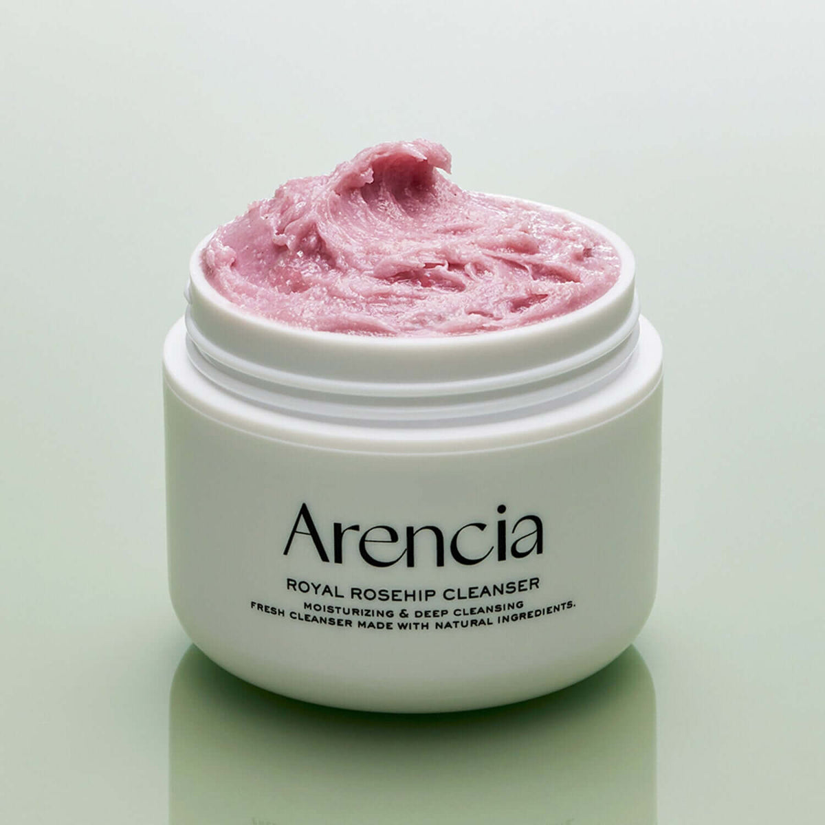 Open jar of ARENCIA Royal Rosehip Fresh Cleanser Rice Soap 120g with pink cream on a green background.