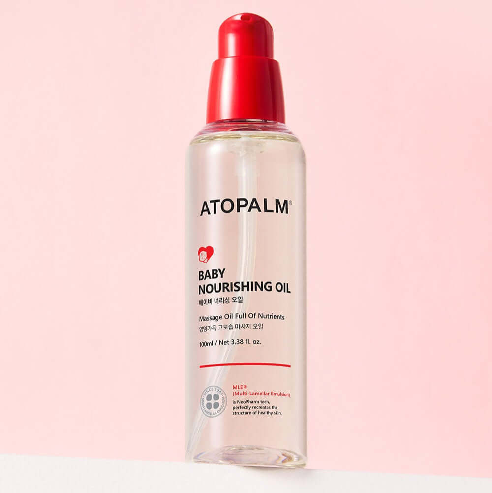 ATOPALM Baby Nourishing Oil 100ml bottle against a pink background, featuring a red cap, designed for gentle baby skin care.