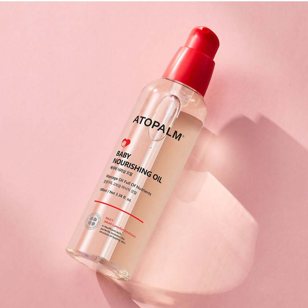 ATOPALM Baby Nourishing Oil 100ml bottle on pink background, skincare product for infants, hydrating and soothing oil for baby care.