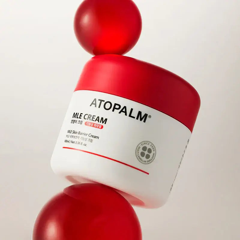 ATOPALM MLE Cream 160ml (Single Type) jar on red spheres, showcasing skincare product packaging.