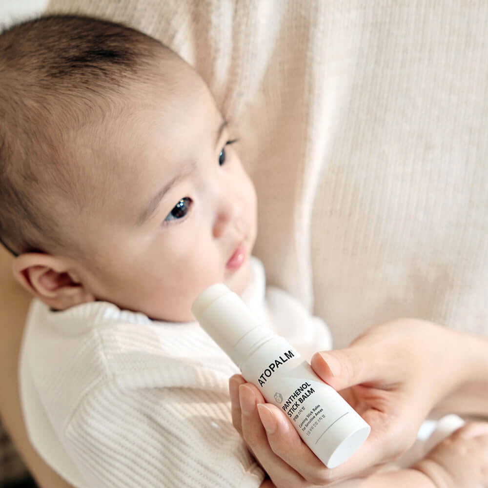 Person holding ATOPALM Panthenol Stick Balm 10g near a baby.