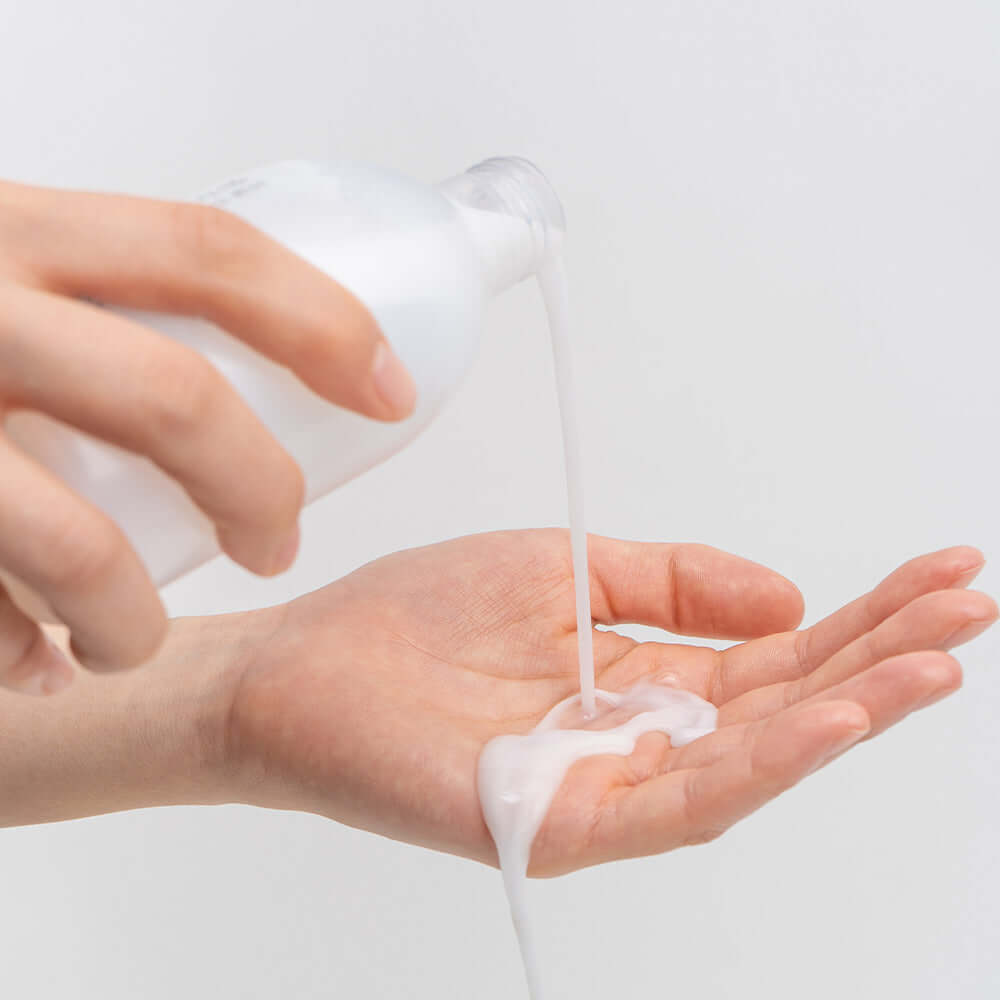 Pouring BARULAB Rice Makgeolli Probiotic Yeast Cream in Essence 200ml into hand for skincare routine.