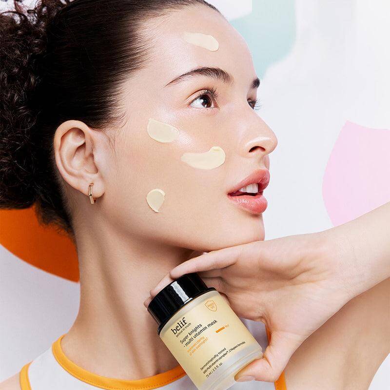 Woman applying BELIF Super Knights Multi Vitamin Mask 75ml on face for nourishment and skincare, holding product jar.