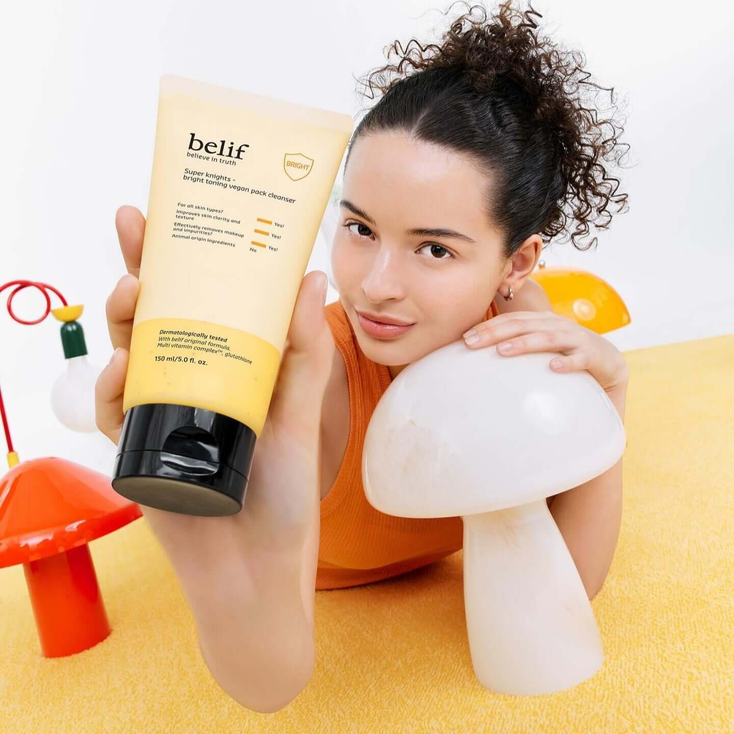 Person holding BELIF Super Knights bright Toning Vegan Pack Cleanser 150ml in a colorful setting.