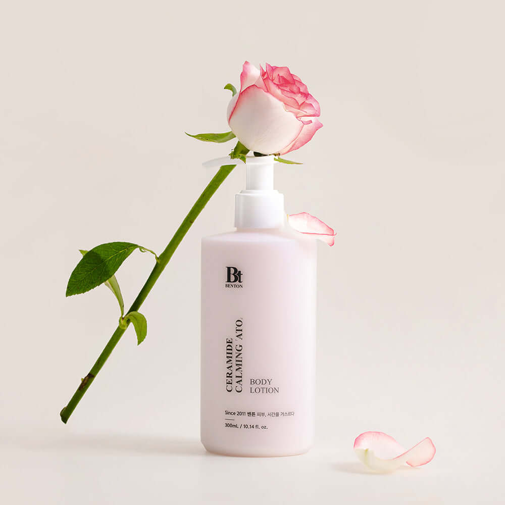 BENTON Ceramide Calming Ato Body Lotion 300ml beside a pink rose on a white background.