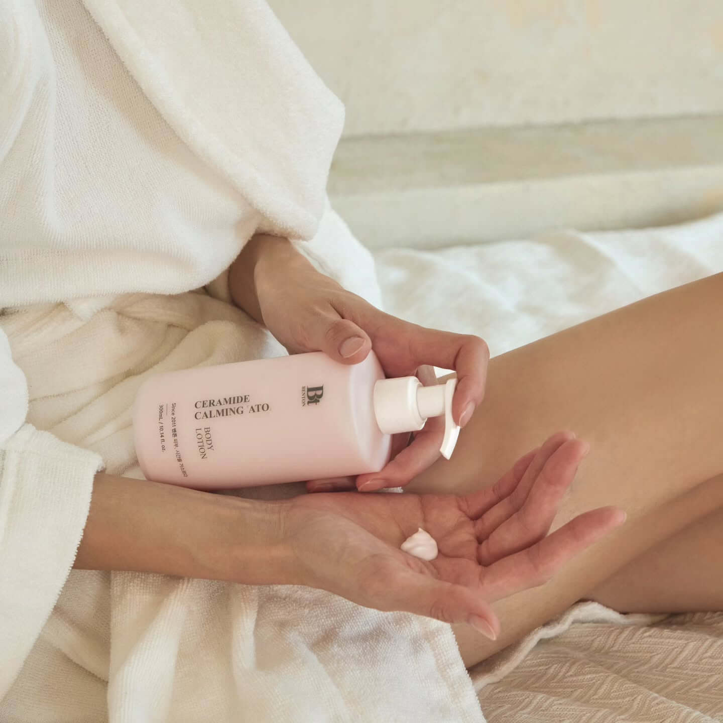 Person applying BENTON Ceramide Calming Ato Body Lotion 300ml, ideal for soothing and hydrating skin, in a serene setting.
