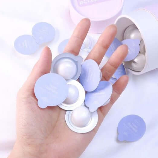 Hand holding capsules from the BLESSED MOON Clean Kit with lid and capsules on table