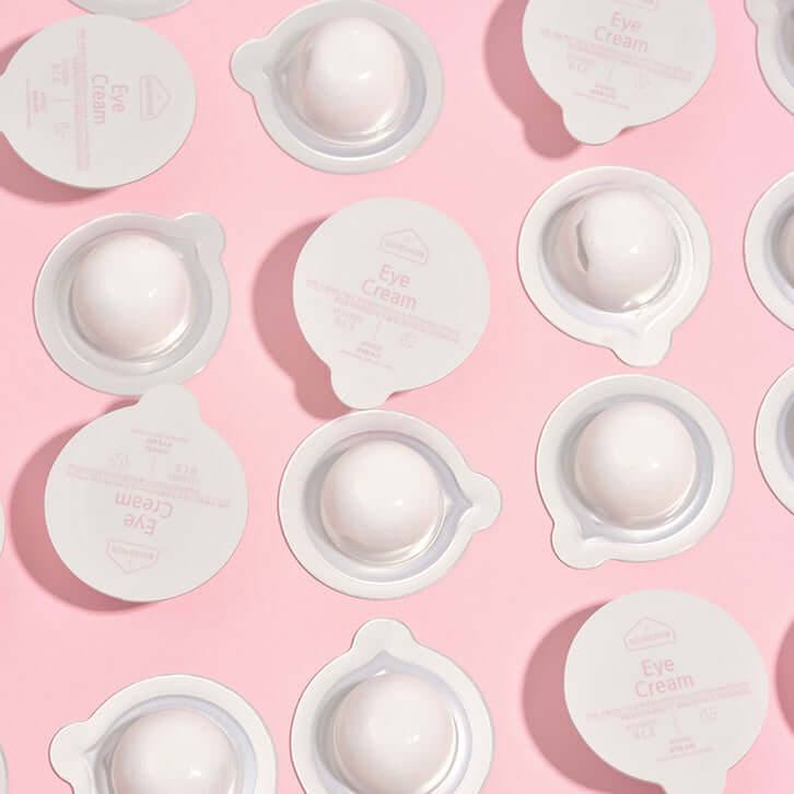 BLESSED MOON Eye Kit eye cream pods on a pink background, showcasing the elegant packaging and design.