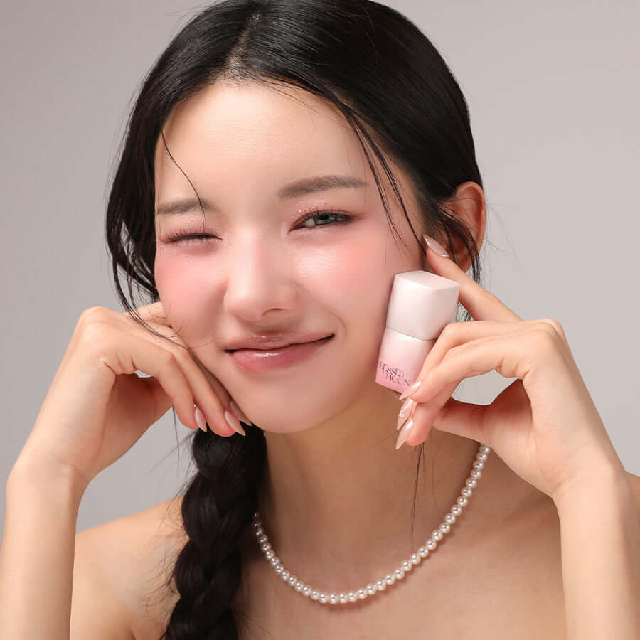 Smiling woman holding BLESSED MOON Veil Melting Color Blush next to her face, showcasing the product's effect on cheeks.