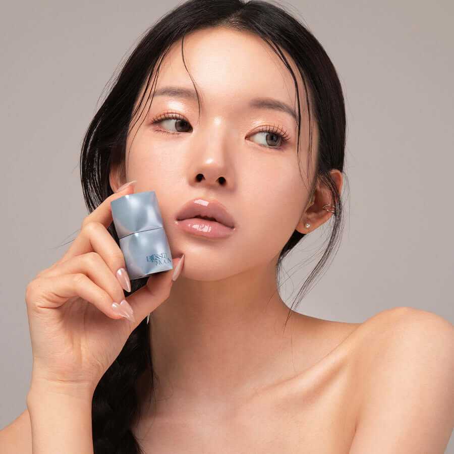 Woman holding BLESSED MOON Veil Mood Lip Gloss, showcasing glossy lips and product packaging.