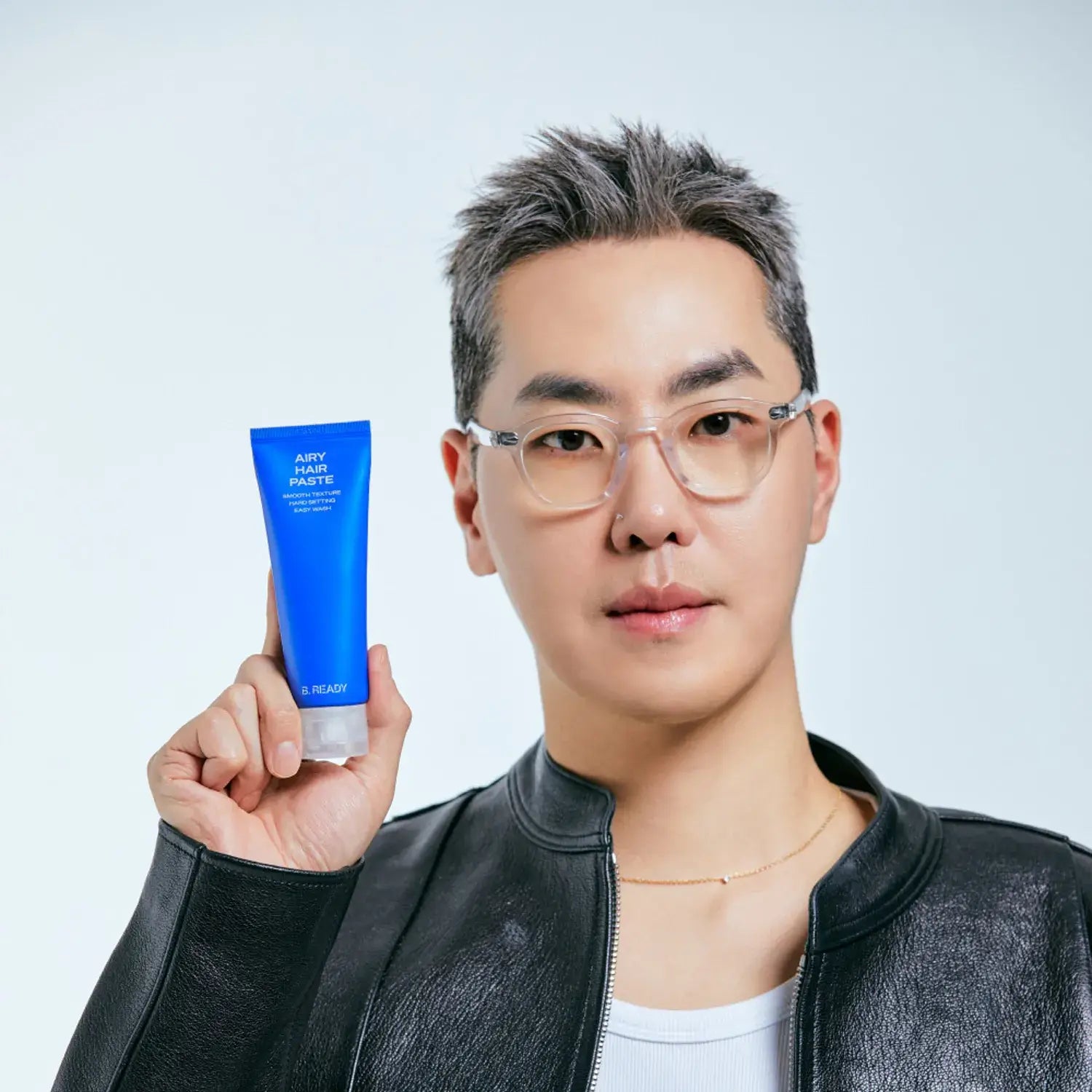 Person holding B.READY Airy Hair Paste 80g in blue tube against a plain background.