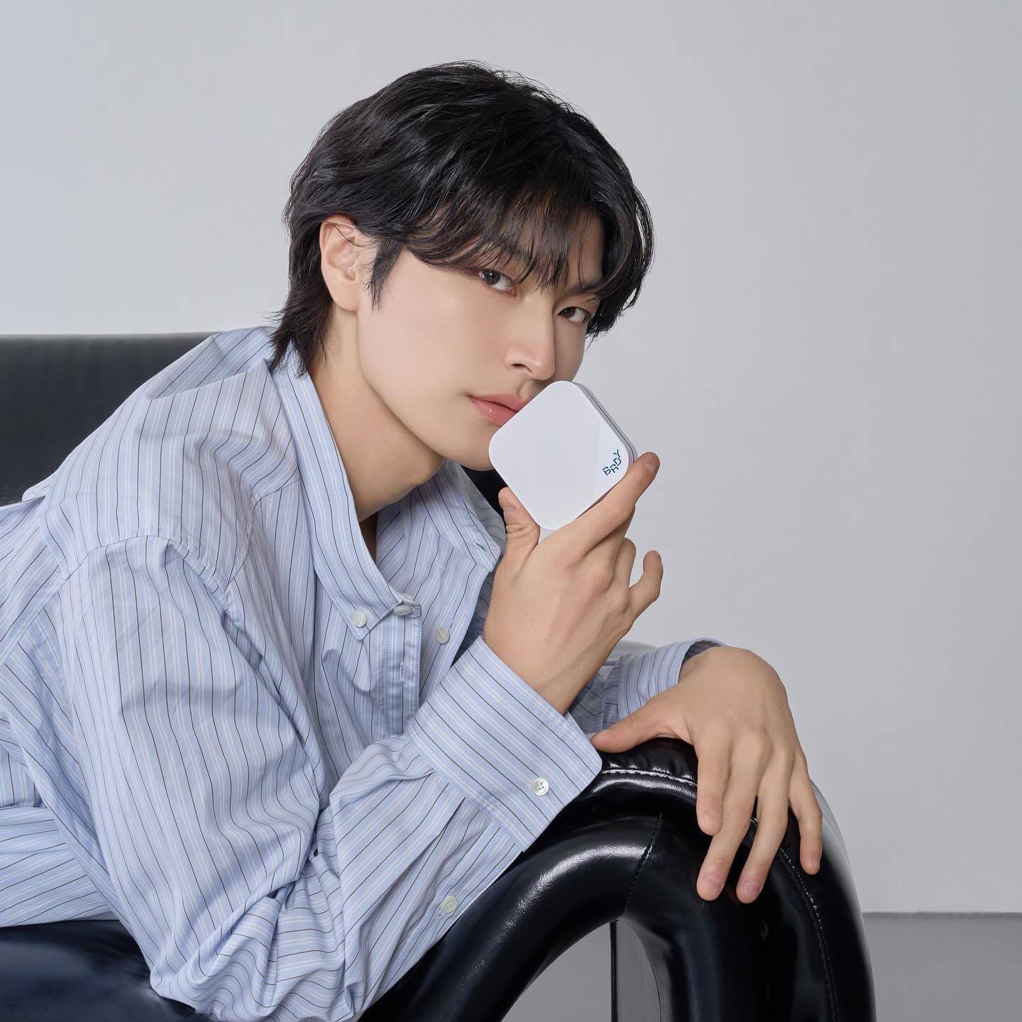 Person holding B.READY Blue Cushion 4th Generation 15g (SPF 34PA++++), showcasing compact design on a black chair.