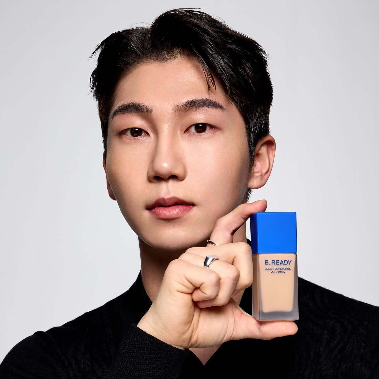 Model holding B.READY Blue Foundation bottle, showcasing the product's sleek design.