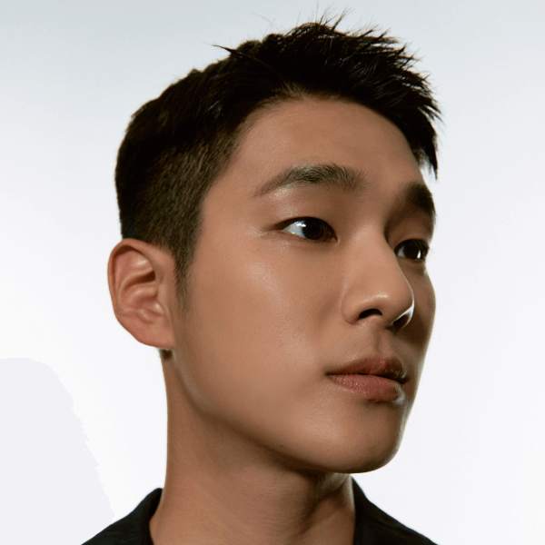 Young man with short black hair looking to the side against white background