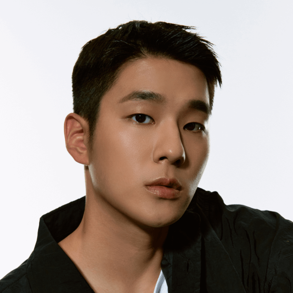 A stylish individual with a confident expression, wearing a black jacket.