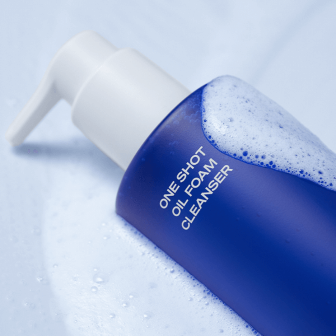Close-up of B.READY Oil Foam Cleanser 200ml bottle with foamy bubbles on a blue surface.