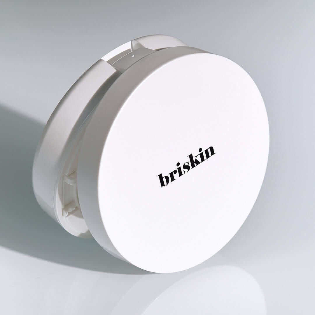 BRISKIN Exo-Glow Secondskin Cushion 15g product photo featuring a sleek white compact with the brand logo on a light background.