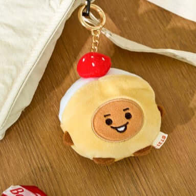 BT21 Bakery Plushy Keyring on wooden surface with red cherry detail.