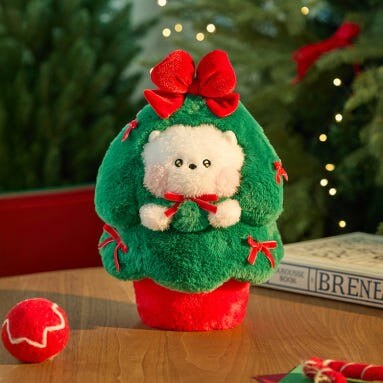 BT21 Minini Petit Holiday Tree Plushy on a table with festive decorations and a Christmas-themed setting.