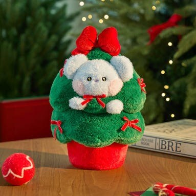 BT21 Minini Petit Holiday Tree Plushy displayed on a table with festive decorations and books in a holiday setting.