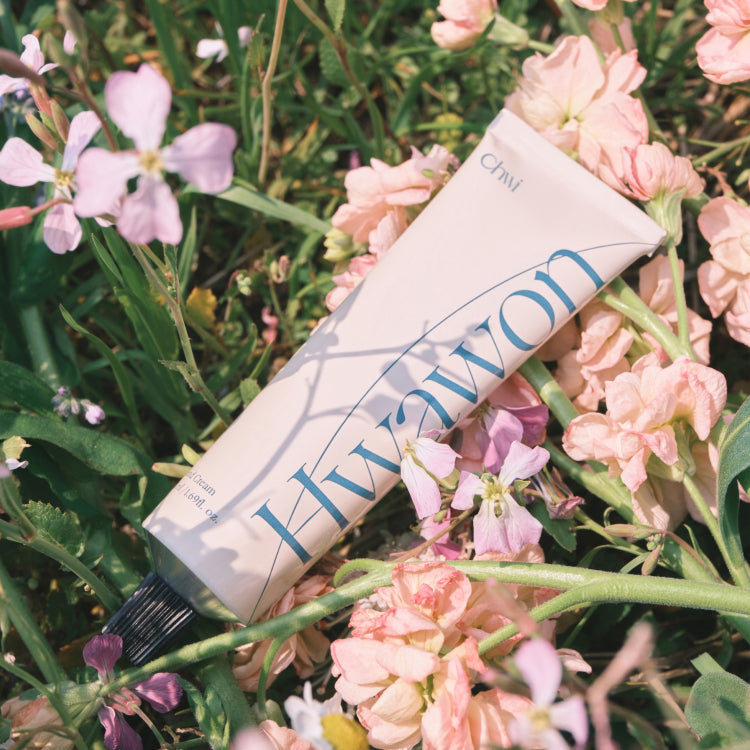 CHWI (CHI) Hwa Won Hand Cream 50ml tube surrounded by pastel flowers in a garden setting.