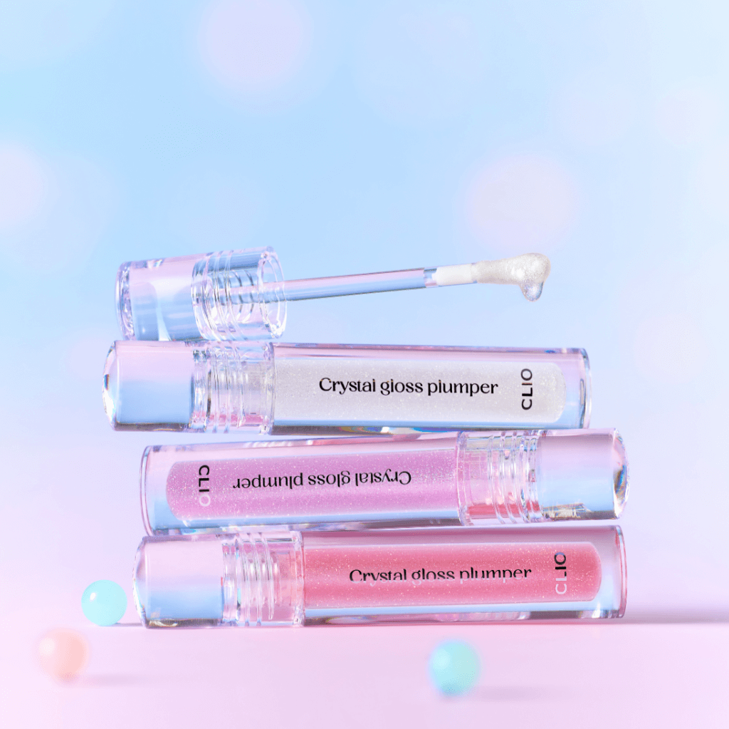 CLIO Crystal Gloss Plumper stacked tubes with applicator on pastel background, showcasing glossy finish and plumping effect.