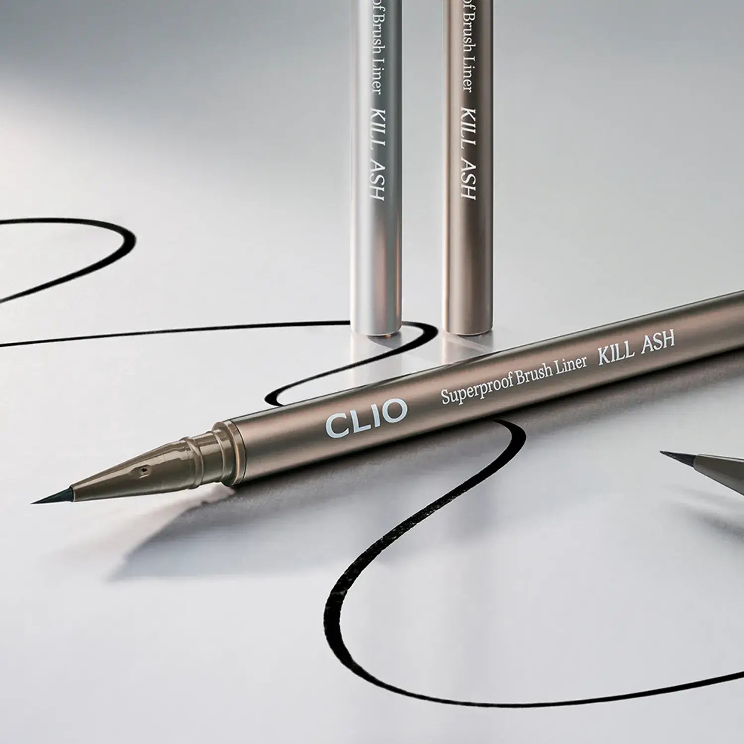 Image of CLIO Superproof Brush Liner Kill Ash, highlighting its precise tip and elegant packaging on a reflective surface.
