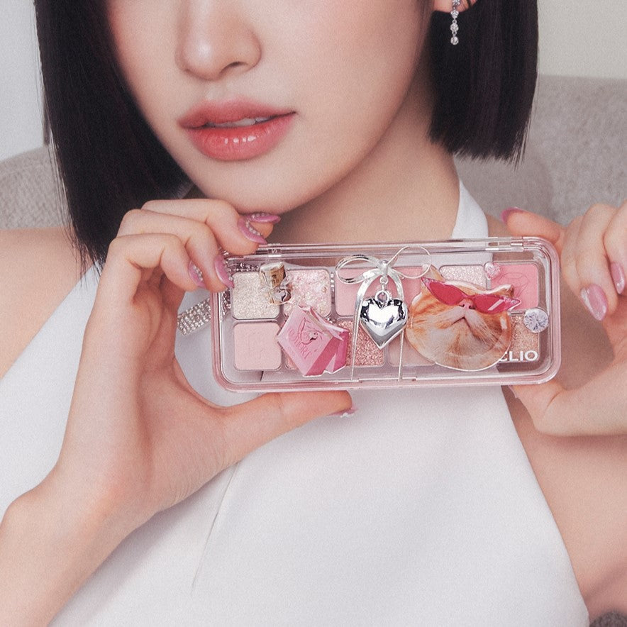 Woman holding CLIO Pro Eye Palette Air (#01 to #15) with pink and brown shades, featuring a decorative charm.