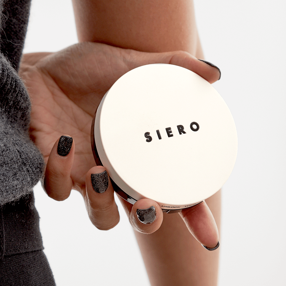 Hand holding COSIERO Coco Aqua Black Cushion in elegant packaging, showcasing premium cosmetic product.