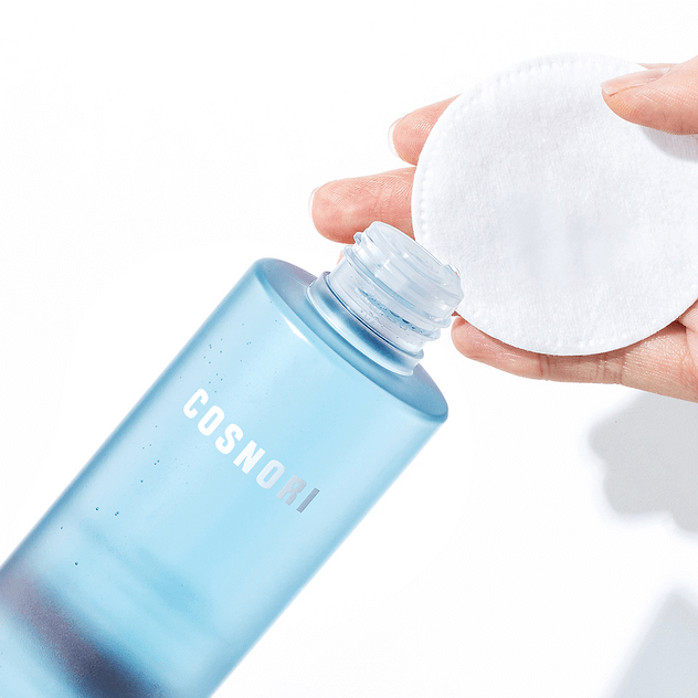 COSNORI Hyaluronic Moisture Toner 200ml being poured onto a cotton pad for skincare routine.
