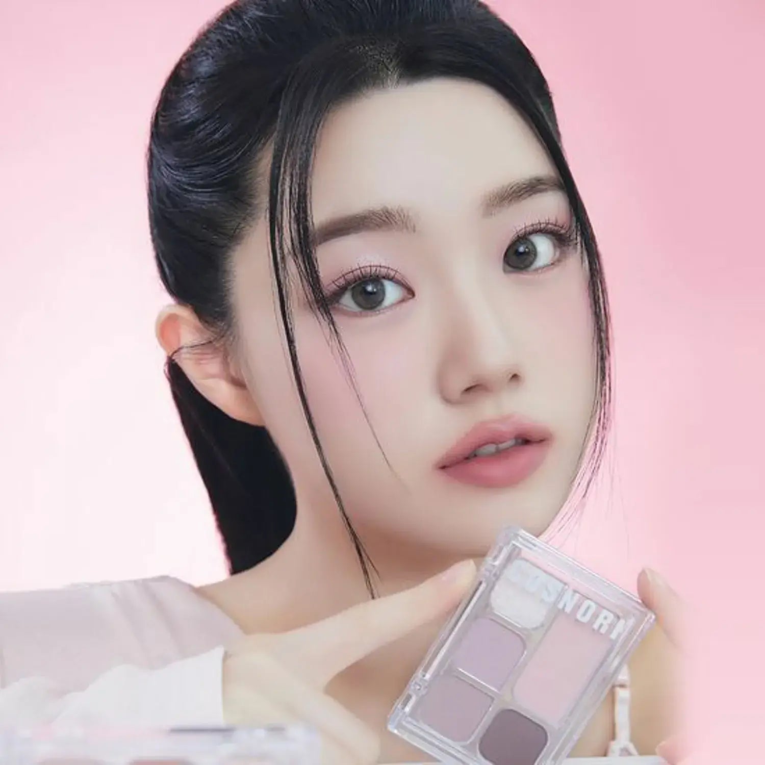 Woman showcasing COSNORI My Moment Eye Palette with a soft pink background.