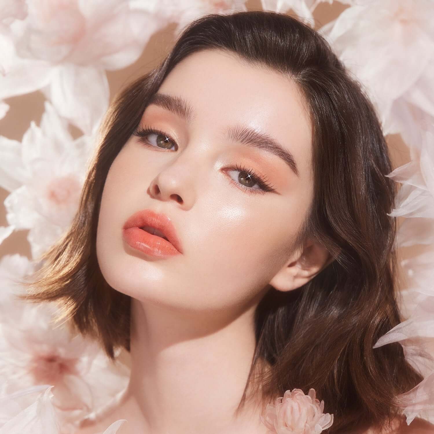 Model wearing DEAR DAHLIA Blooming Edition Glass Shine Lip Topper surrounded by flowers