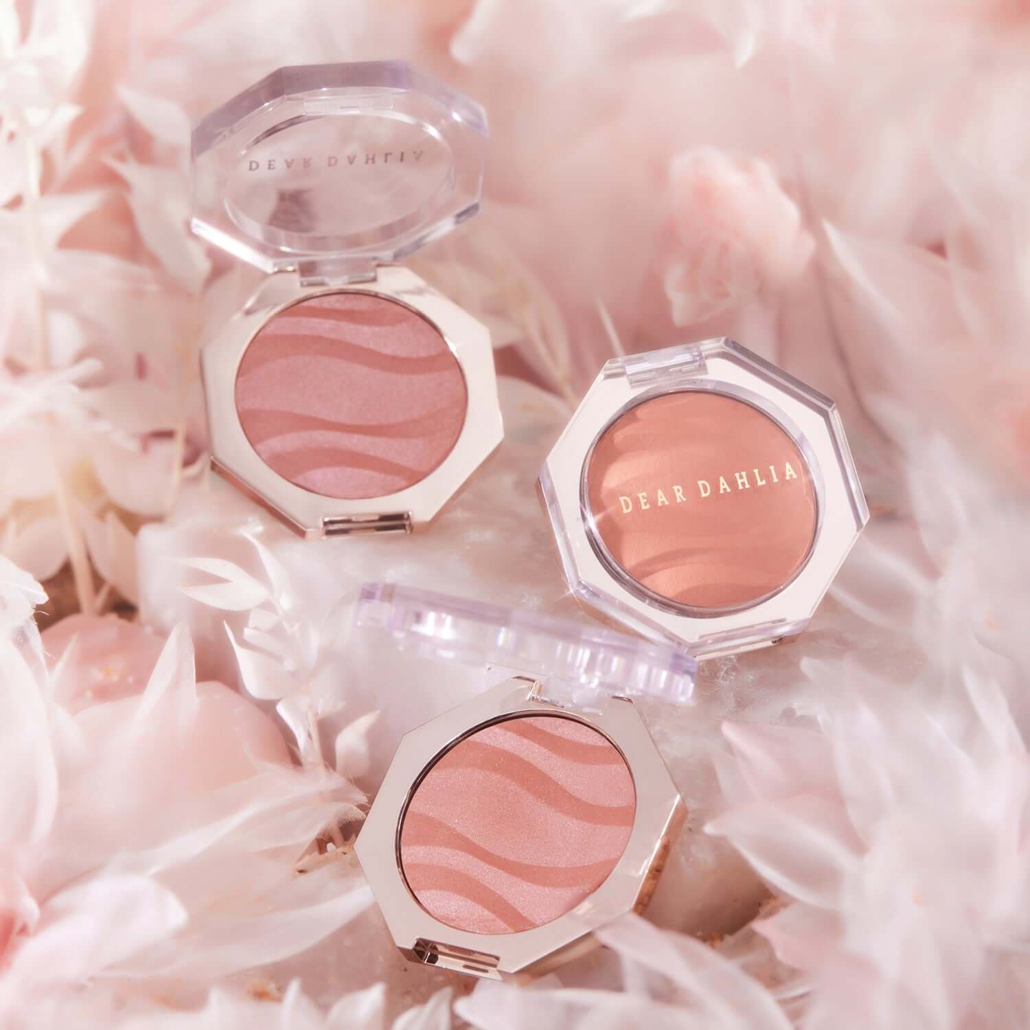 DEAR DAHLIA Blooming Edition Petal Glow Blush surrounded by soft pink petals, showcasing luxury cosmetic packaging